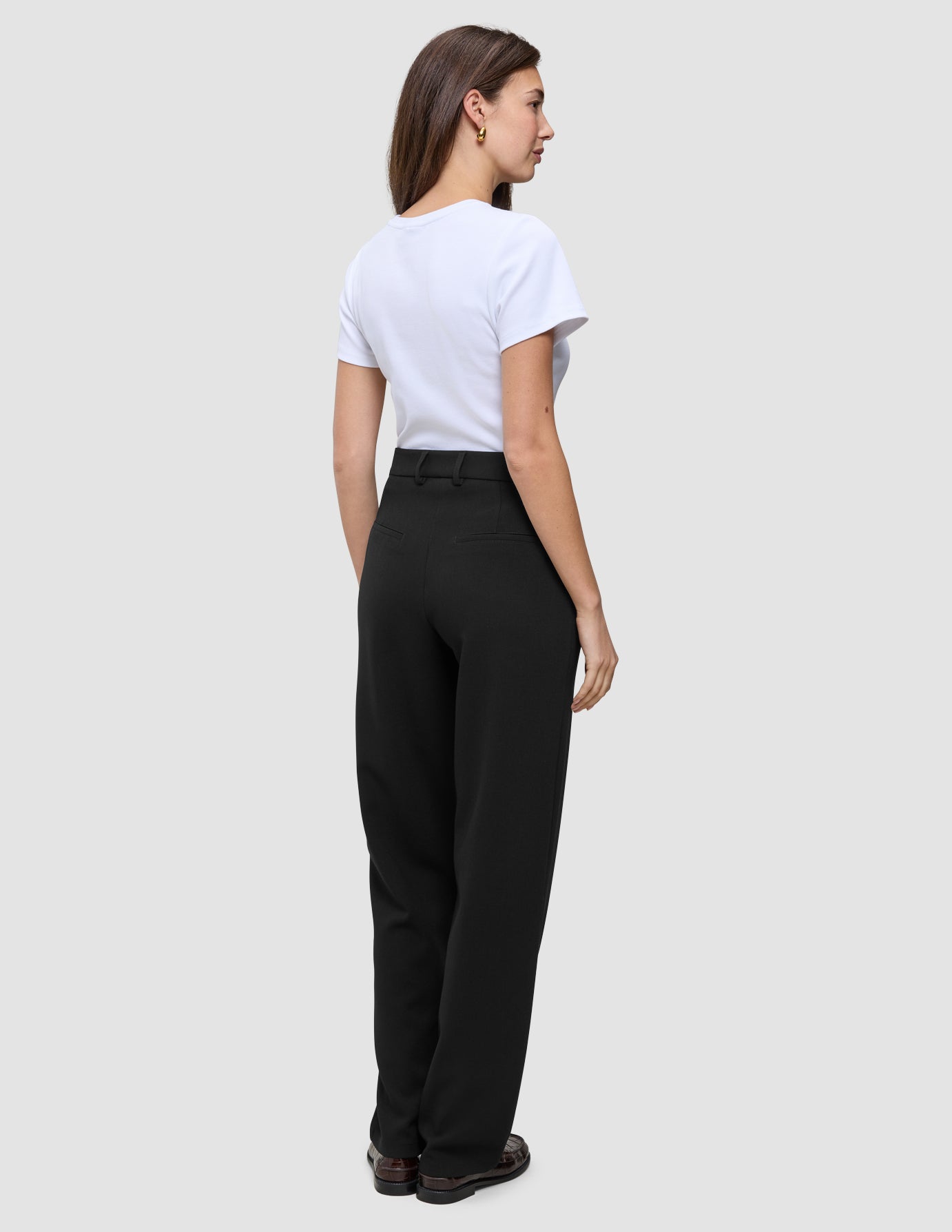 En kvinde set bagfra iført en hvid T-shirt og sorte Women GO2 Pants Straight med lige ben.